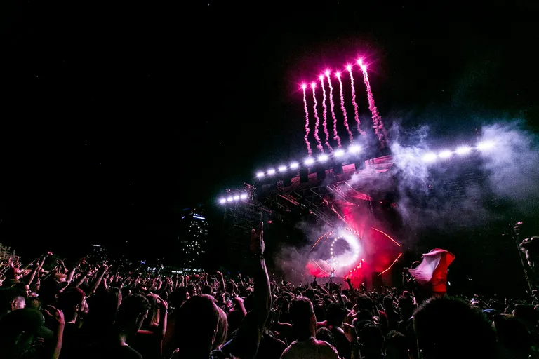 A vibrant concert scene with a large audience cheering under colorful pyrotechnics and dynamic stage lighting, creating an electrifying atmosphere.