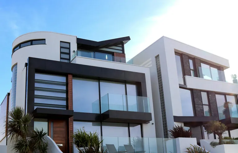Modern two-tone residential buildings featuring large windows and balconies, set under a sunny sky.